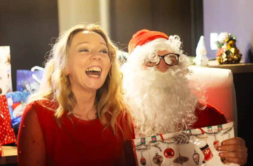 Radosna kobieta z Mikołajem, który rozdaje prezenty, co jest częścią pakietu bożonarodzeniowego w górach.